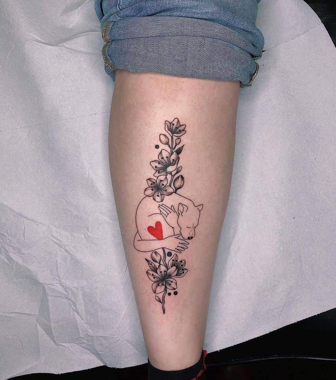 Arms Hugging Dog and Flowers Tattoo